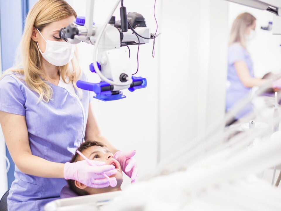 young female dentist examining boy s teeth through microscope 23 2147906006